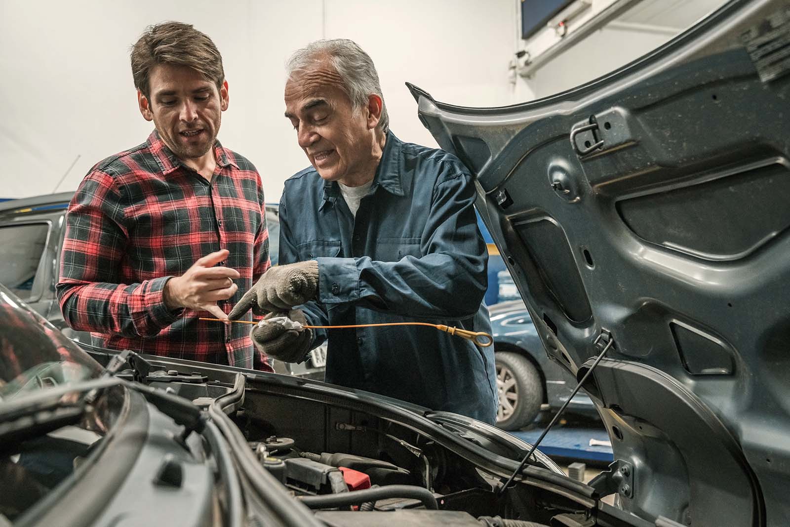 Men working in a garage and inspecting a car engine